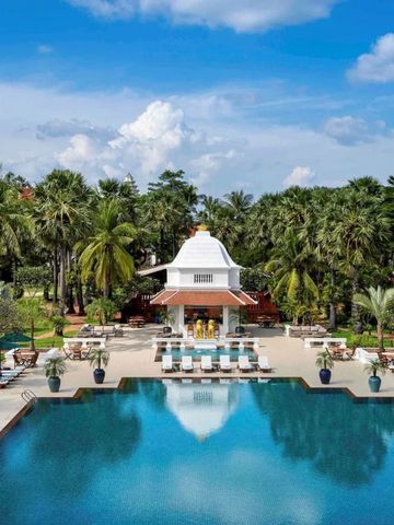 Großer Pool mit eleganter Poolbar umgeben von Palmen und blauem Himmel