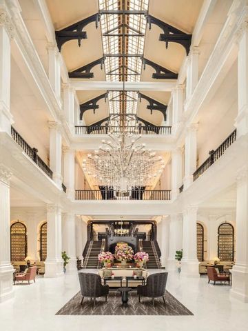 Opulente Lobby des Raffles Singapore mit großem Kronleuchter und Marmorsäulen.