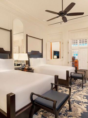 Zimmer mit zwei großen Betten, stilvollen Möbeln und einem eleganten Teppich.