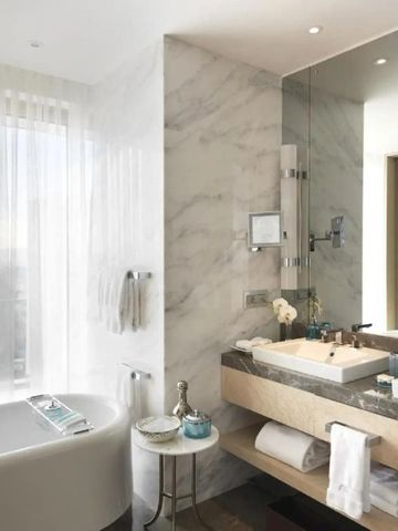 Luxuriöses Badezimmer mit Marmorwänden und großer Badewanne