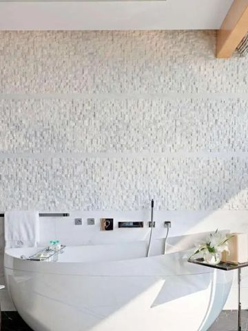 Helle Badezimmer mit freistehender Badewanne und Natursteinwand.