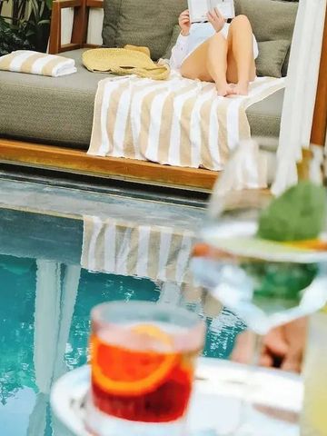 Frau entspannt auf einer Pool-Liege mit Getränken im Vordergrund