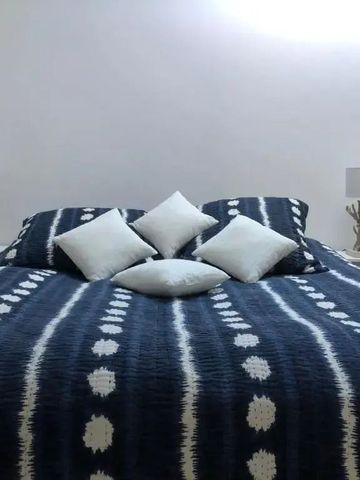 Modernes Schlafzimmer mit blau-weiß gemustertem Bett und eleganter Beleuchtung