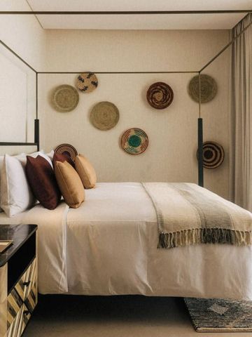 Modernes Schlafzimmer mit Himmelbett und dekorativen Wandkörben. Helles und einladendes Design.