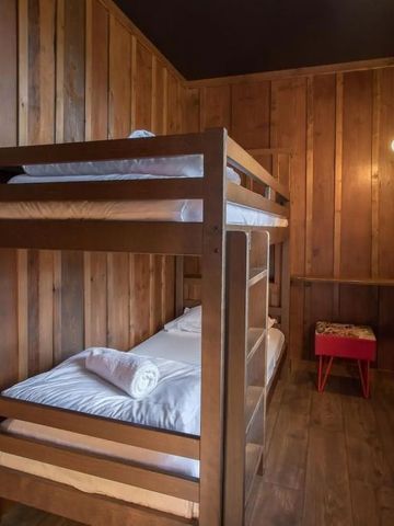 Holzvertäfeltes Zimmer mit Etagenbett und rotem Hocker