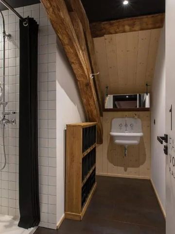 Badezimmer mit Dusche und Holzdeckenbalken.