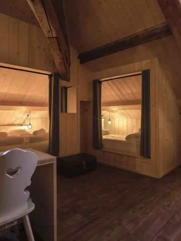 Gemütliches Holzzimmer mit zwei erleuchteten Bettbereichen und einem Schreibtisch.