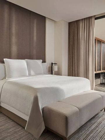 Modernes Hotelzimmer mit großem Bett und angrenzendem Balkon.