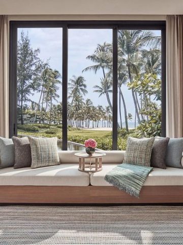 Gemütliche Sitzecke mit Gartenblick auf Palmen und das Meer