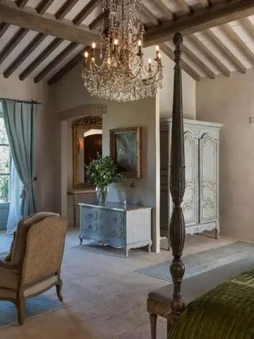 Elegantes Schlafzimmer mit Holzbalkendecke und Kronleuchter in sanften Farben dekoriert