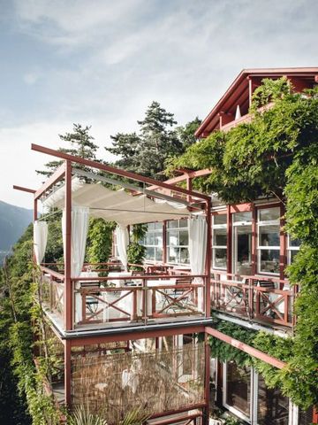 Romantische Terrasse mit Ausblick auf die Berge und grüner Vegetation an der Fassade