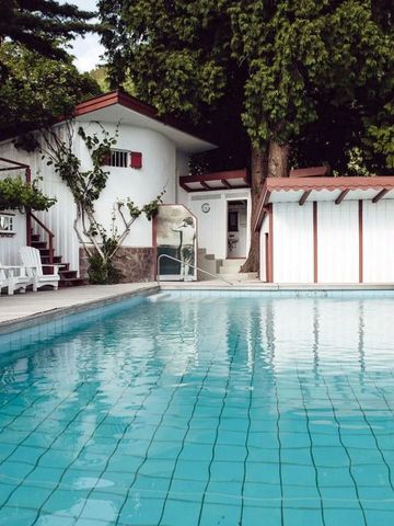 Außenpool in ruhiger Gartenumgebung mit weißen Liegen und Bäumen