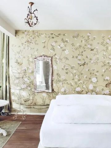 Elegantes Zimmer mit floraler Tapete und antikem Spiegel