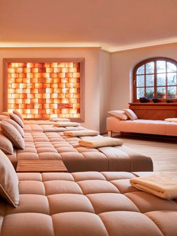 Ruheraum mit luxuriösen Liegen und einer beleuchteten Salzsteinwand im Hotel Tennerhof.