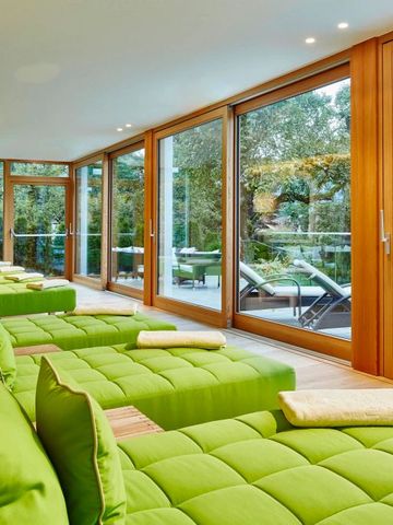 Heller Wellnessbereich mit grünen Liegen und großen Fenstern