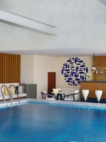 Indoor-Pool mit blauer Wanddekoration und moderner Bar im Hintergrund