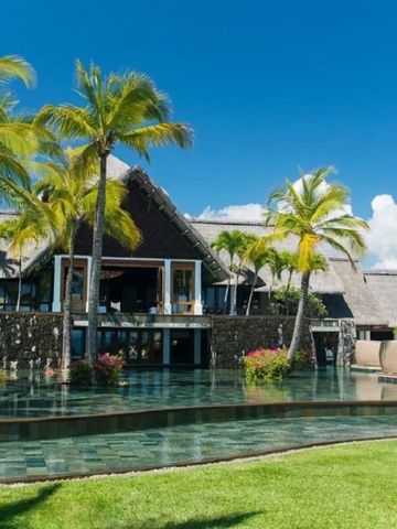 Hotelgebäude mit Palmen und Wasserflächen im Vordergrund