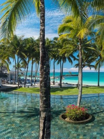 Poollandschaft mit Palmen am Strand bei klarem Himmel