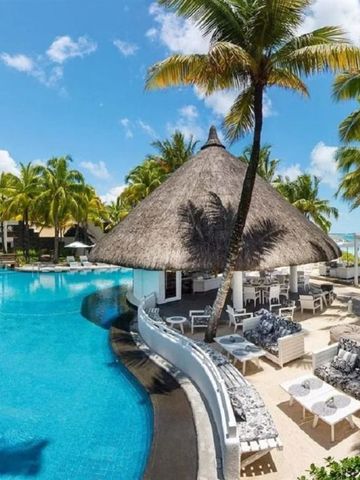 Tropischer Poolbereich mit Palmen und Strand im Hintergrund