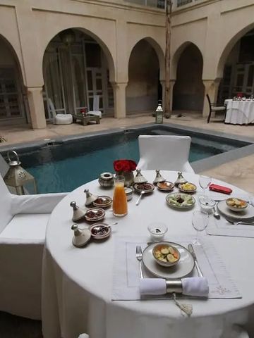 Frühstückstisch am Pool in einem ummauerten Innenhof