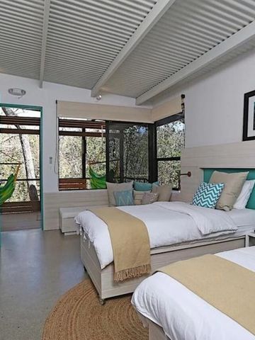 Helles Hotelzimmer mit zwei Betten und Zugang zu einem Balkon mit Hängematten