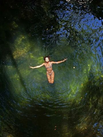 Person schwimmt in einem natürlichen Thermalbecken im Freien