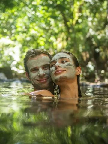 Paar mit Gesichtsmasken entspannt im Fluss inmitten des Waldes