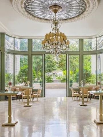 Heller, luxuriöser Raum mit großem Kronleuchter und Blick auf Garten