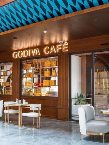 Gemütliches Café mit Sitzbereich und Godiva-Schriftzug.