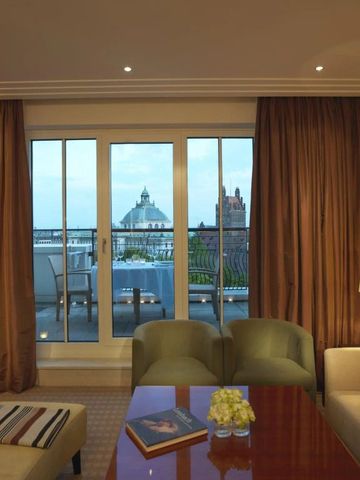 Hotelsuite mit Blick auf Terrasse und Stadtpanorama bei Abenddämmerung.
