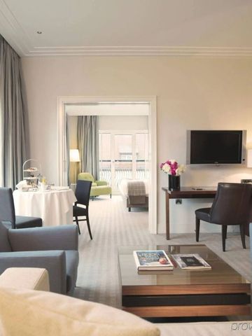 Luxuriöses Wohnzimmer einer Suite mit eleganten Möbeln und großem Fenster.