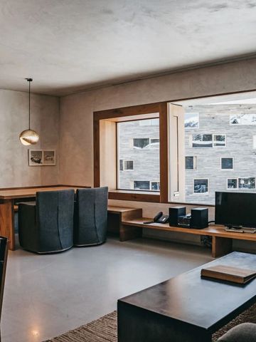 Modern eingerichtetes Wohnzimmer mit großen Fenstern und Blick auf ein Gebäude