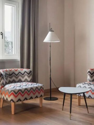 Moderner Sitzbereich mit gemusterten Sesseln und Lampe neben einem Fenster