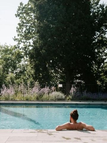 Person entspannt sich im Pool mit Blick auf die umliegende Natur
