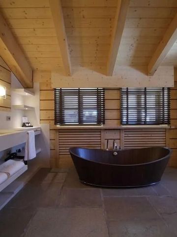 Geräumiges Badezimmer mit freistehender Badewanne unter Holzdecke.