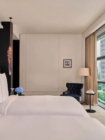 Helles Hotelzimmer mit zwei Betten und großem Fenster mit Blick auf grüne Umgebung