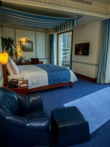 Luxuriöses Zimmer mit großem Bett und ledernem Sessel im Rosewood Jeddah.