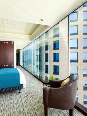 Helles Zimmer mit großer Glasfront und Blick auf die Gebäude