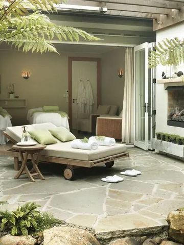 Luxuriöser Spa-Bereich mit offenen Türen zum Garten und Liege mit Handtüchern