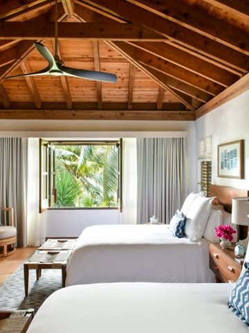 Helles Schlafzimmer mit zwei Betten und Aussicht auf tropische Vegetation