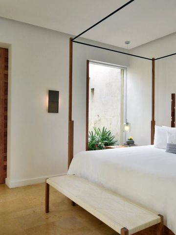 Modernes Schlafzimmer mit Himmelbett und Zugang zu einem hellen Badezimmer