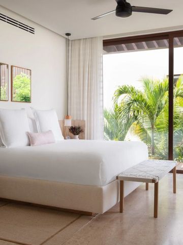 Helles Schlafzimmer mit großen Glasfenstern und Ausblick auf tropische Vegetation