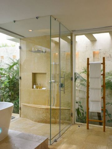 Luxuriöses Badezimmer mit Glasdusche und grüner Aussicht.