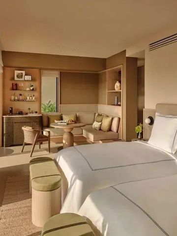 Helles Hotelzimmer mit zwei Betten und einem Sitzbereich.