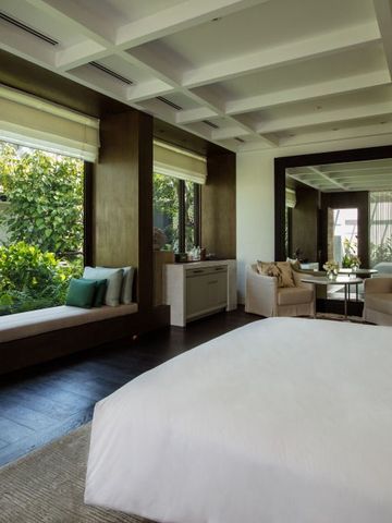 Großzügiges Schlafzimmer mit gemütlicher Sitzgelegenheit und Gartenblick