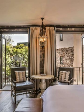 Zimmer mit Balkonblick auf grünen Innenhof und rustikaler Wanddekoration