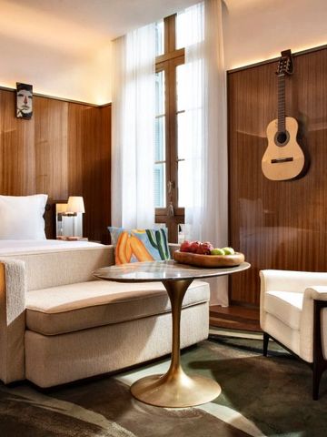 Einladender Sitzbereich im Hotelzimmer mit Wandkunst und Gitarren-Dekoration