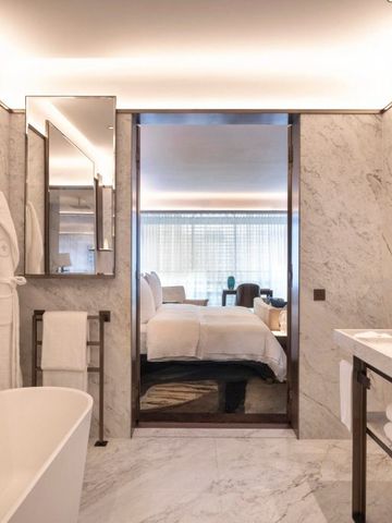 Luxuriöses Badezimmer mit freistehender Badewanne und Blick ins Schlafzimmer