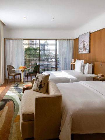 Helles Hotelzimmer mit zwei Betten Holzakzenten und Balkonblick