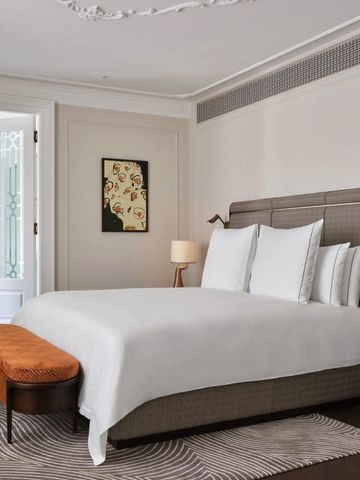 Elegantes Hotelzimmer mit großem Bett, dezenter Kunst und stilvoller Beleuchtung.